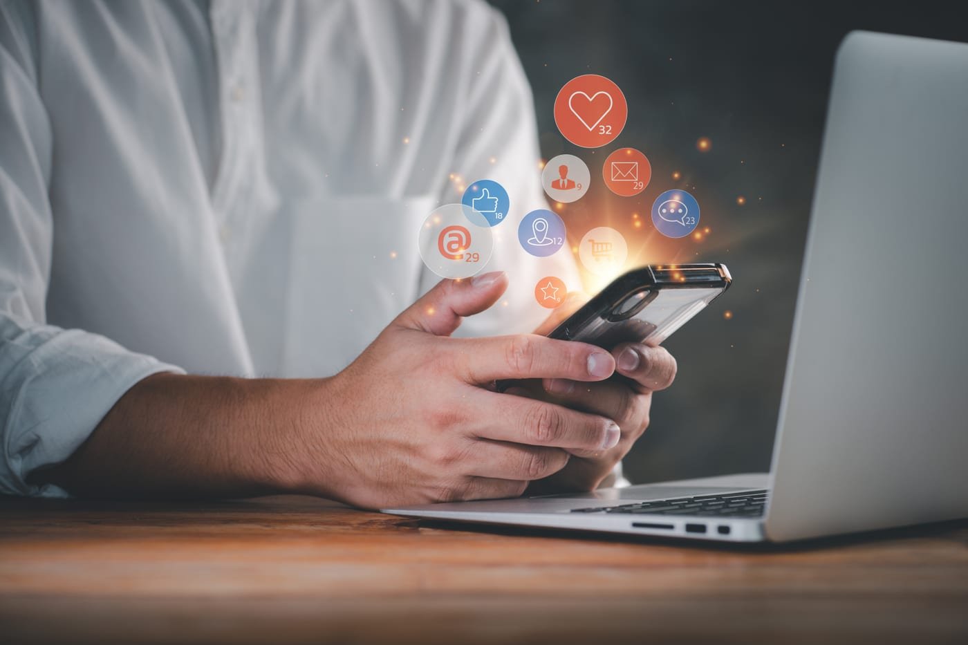 Gestor de tráfego usando o celular com ícones de interações de redes sociais sobrepostos, representando criação de anúncio no Meta Ads por IA